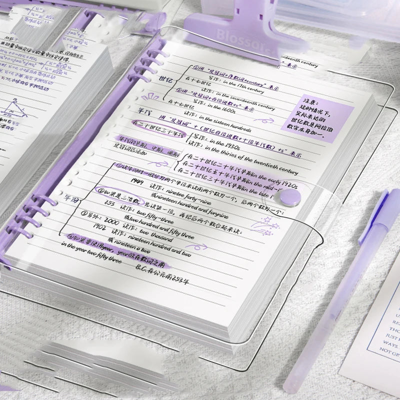 Cuaderno A5 de hojas sueltas (60 hojas/120 páginas) con cubierta de piel sintética flexible y translúcida, anillas desmontables y rayado horizontal.