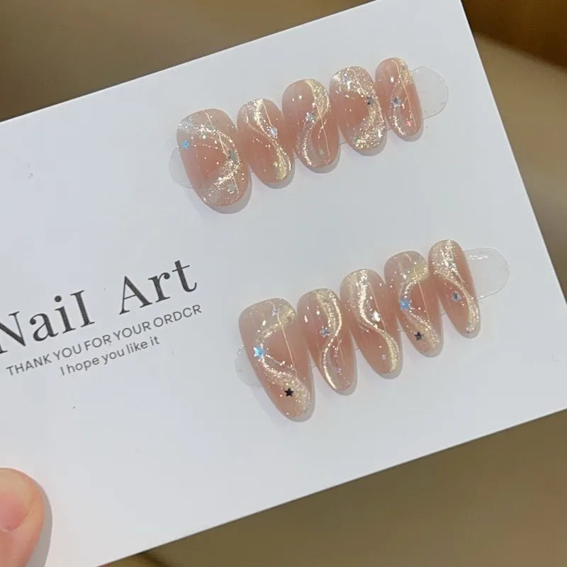 Set de 10 uñas postizas hechas a mano con diseño de lazo, efecto ojo de gato y estrella de cinco puntas; forma ovalada mediana y estilo de aplicación a presión (press-on). Ideal como regalo para chicas.