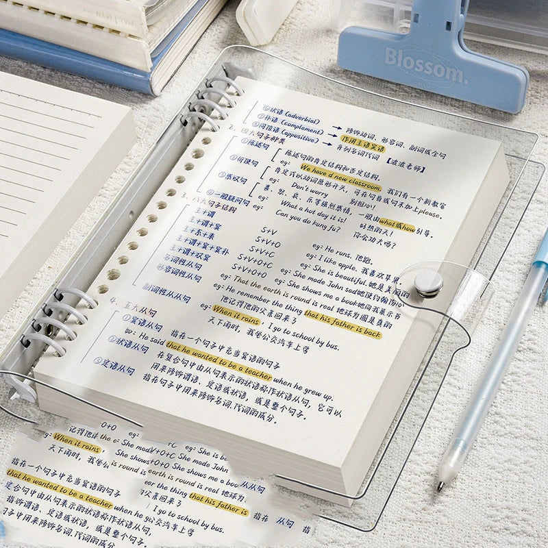 Cuaderno A5 de hojas sueltas (60 hojas/120 páginas) con cubierta de piel sintética flexible y translúcida, anillas desmontables y rayado horizontal.