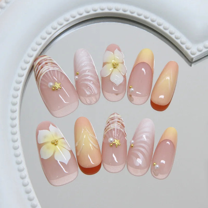 Uñas almendradas hechas a mano con degradado rosa *nude*, decoradas con conchas en 3D, flores de plumeria y perlas. Reutilizables, perfectas para el día a día.