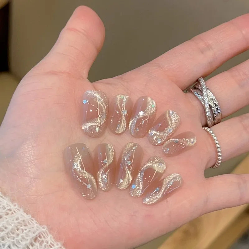 Set de 10 uñas postizas hechas a mano con diseño de lazo, efecto ojo de gato y estrella de cinco puntas; forma ovalada mediana y estilo de aplicación a presión (press-on). Ideal como regalo para chicas.